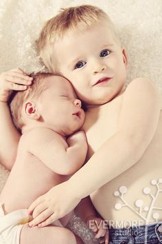 two babies are cuddling together in the middle of their arms, one is holding the other