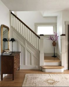 there is a vase with flowers on the table next to the stairs in this house