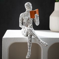 a paper mache sitting on top of a white block next to a potted plant