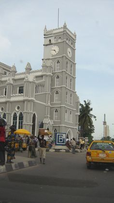 a large white building with a clock on it's face and people walking around