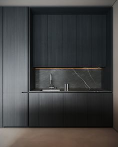 an empty kitchen with black cabinets and marble counter tops, along with a stainless steel sink