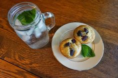 two cookies with blueberries and mint on a plate next to a glass of water