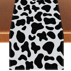 a cow print table runner on top of a wooden table with white and black trim