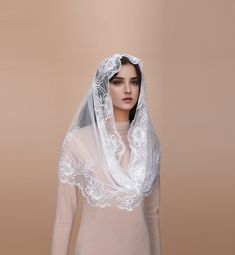 a woman wearing a veil and dress with white flowers on the head is standing in front of a beige background