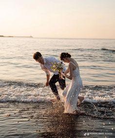 a bride and groom are playing in the water at their beach wedding ceremony on the ocean