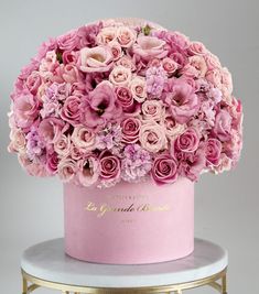 a pink hat with flowers in it on top of a white table next to a gold stand