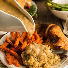 someone is pouring gravy over some food on a plate with sweet potatoes and carrots