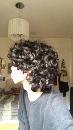 a person with curly hair in a bedroom