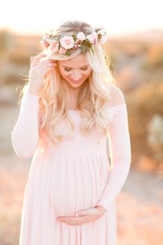 an image of a pregnant woman wearing a flower crown and holding her hands on her head