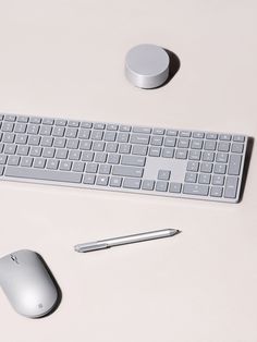 a keyboard, mouse and pen on a white surface with the same color as it appears in this image