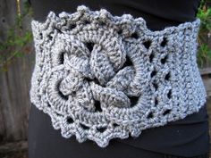 a woman wearing a gray crochet scarf with an intricate design on it's waist