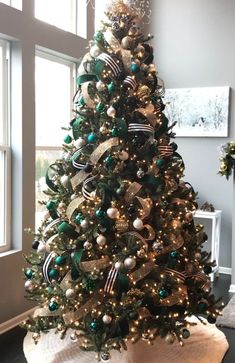 a christmas tree with green and gold ornaments in a living room next to a window