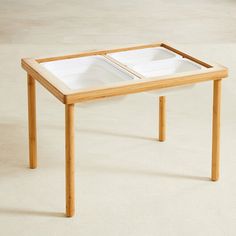 a wooden table with two white dishes on it's top and one is empty