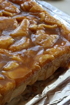 a piece of bread covered in caramel sauce on top of aluminum foil with spoon