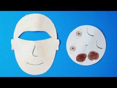 two paper masks with eyes and nose drawn on them sitting next to each other in front of a blue background