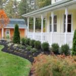 a yellow house with white trim and columns on the front porch is surrounded by green grass