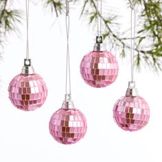 three pink disco ball ornaments hanging from a tree