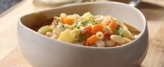 a white bowl filled with pasta salad on top of a wooden table