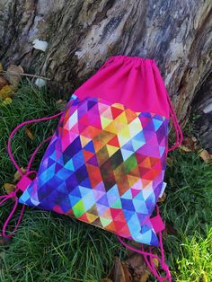 a colorful bag sitting in the grass next to a tree