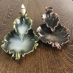 two dishes sitting on top of a wooden table next to each other and one has a candle in it