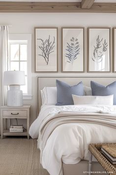 a bedroom with white bedding, blue and gray pillows and pictures on the wall