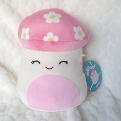 a pink and white stuffed animal with flowers on it's cap, sitting on a bed