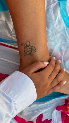 a woman's arm with a turtle tattoo on her left wrist and right hand