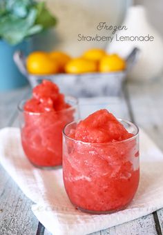 two glasses filled with watermelon ice cream on top of a white napkin next to some lemons