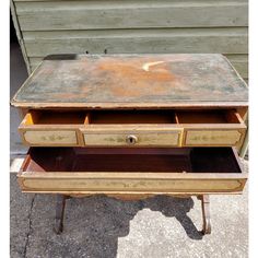 an old wooden desk with drawers on the bottom and one drawer open to reveal something