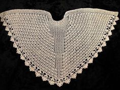 a white crocheted shawl on a black background