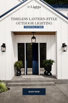 the entrance to a white building with blue door and black potted plants in front