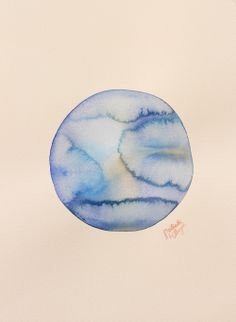 a blue and white circular painting with watercolors on it's surface in front of a beige background