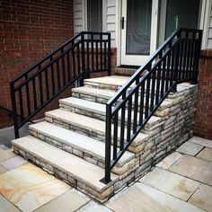 a set of stairs leading up to a brick building with black railings and handrails