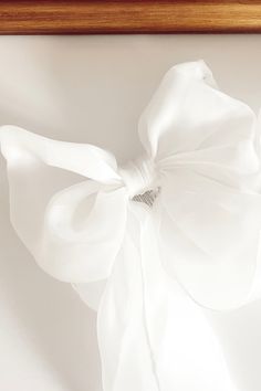 a white bow hanging from the side of a wooden framed artwork piece on a wall