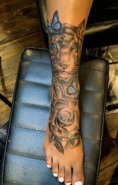 a woman's foot with a tiger tattoo on it and roses around the ankles