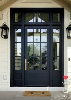 a black front door with two lights on each side and an entry mat underneath it