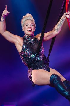 a woman with tattoos on her arm and legs hanging from a pole in the air