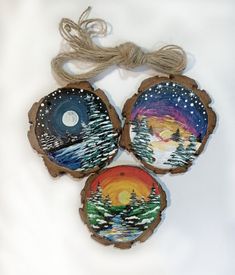 three wood slices with painted trees and the moon in the sky on them are hanging from twine strings