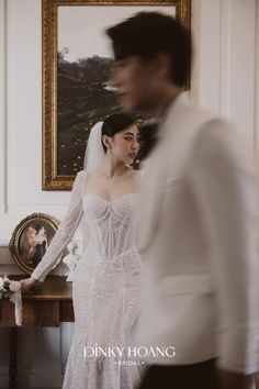 a woman in a wedding dress standing next to a man