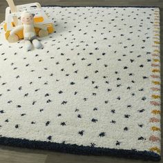 a child's rug on the floor with a toy car and teddy bear next to it