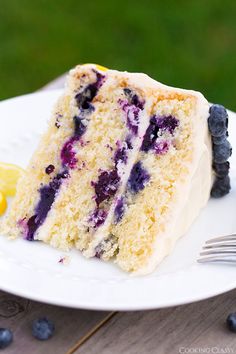 a slice of blueberry cake on a white plate with a fork next to it