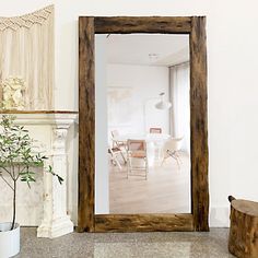 a mirror sitting on top of a wooden table next to a potted plant in front of a fireplace