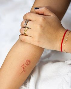 a woman's arm with a small red rose tattoo on the left side of her arm