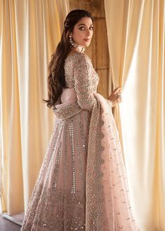 a woman in a pink gown standing next to curtains