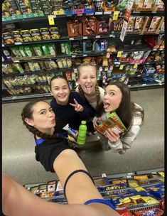 four girls standing in front of a grocery store counter and pointing at the camera with their hands