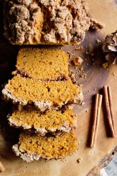 several pieces of cake sitting on top of a wooden cutting board next to cinnamon sticks