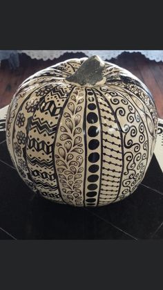 a decorative pumpkin sitting on top of a wooden floor next to a black and white rug