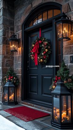 two christmas wreaths on the front door of a house with lit candles and lanterns