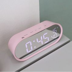 a pink alarm clock sitting on top of a table