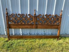 an old wooden bench sitting in front of a metal fence on the side of a building